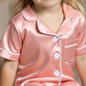 Niño feliz usando unas suaves pijamas en satín para niños color rosado de Lificotex.